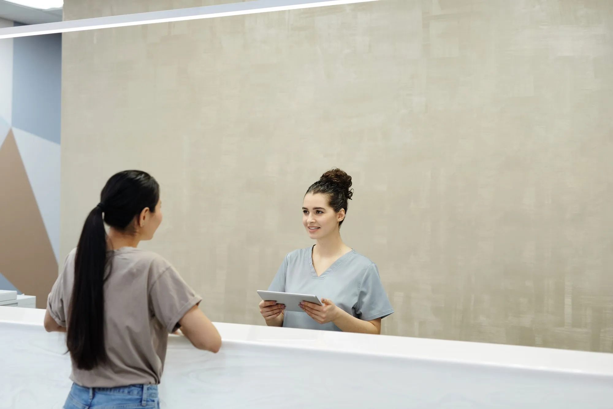 A receptionist greeting a visitor at a clinic desk