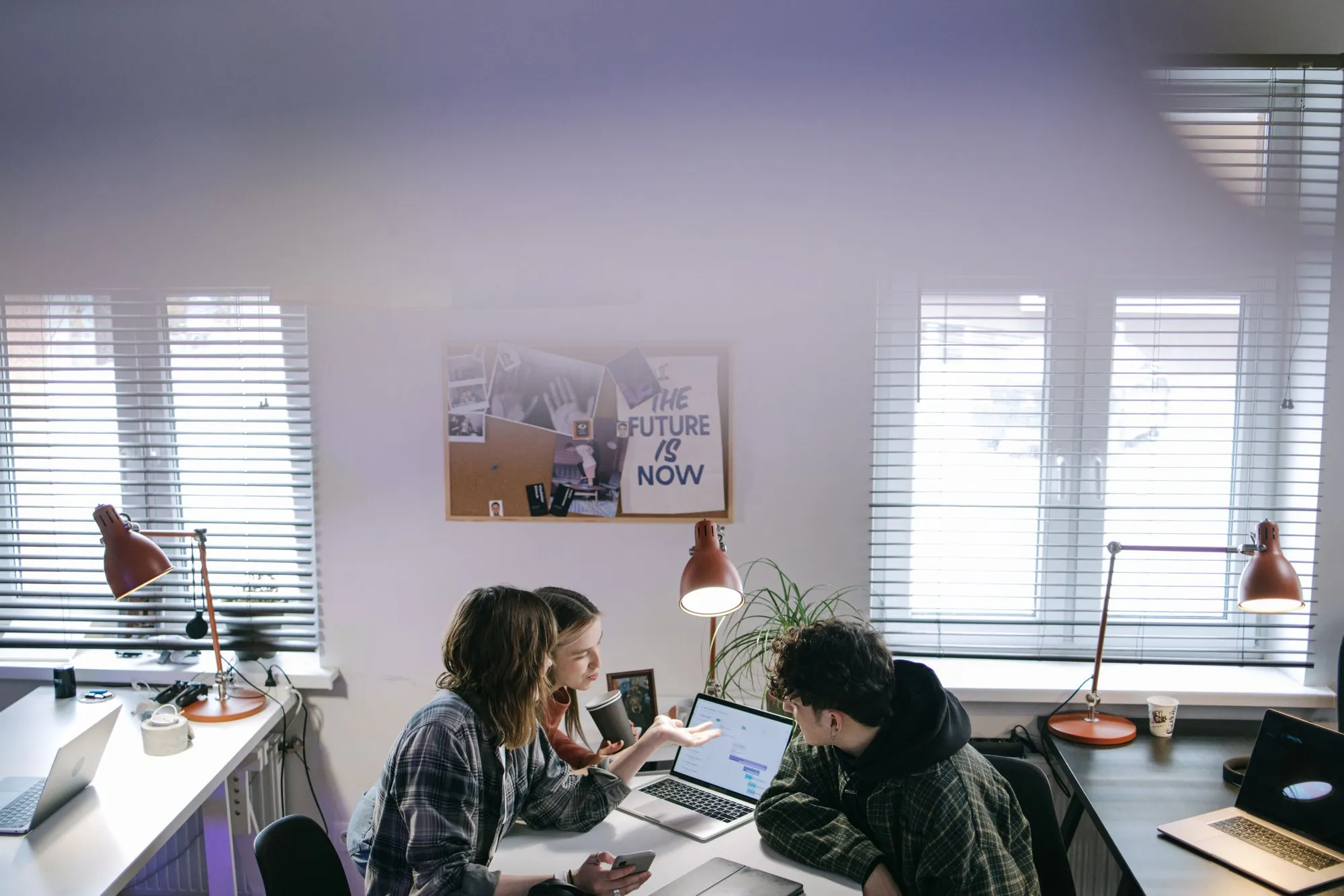 Two people working together at a desk by a window
